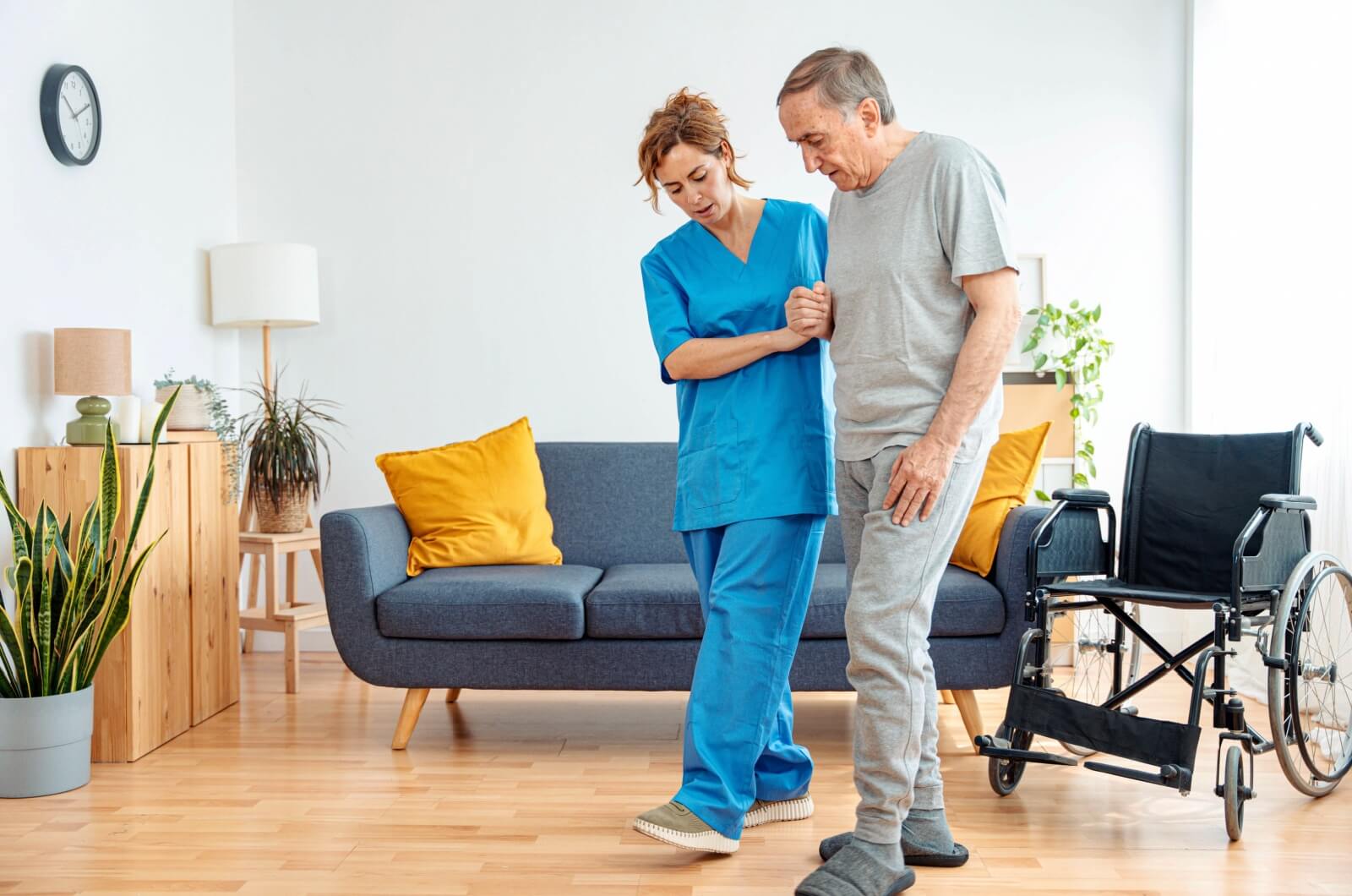 A staff member in assisted living helping an older adult walk.