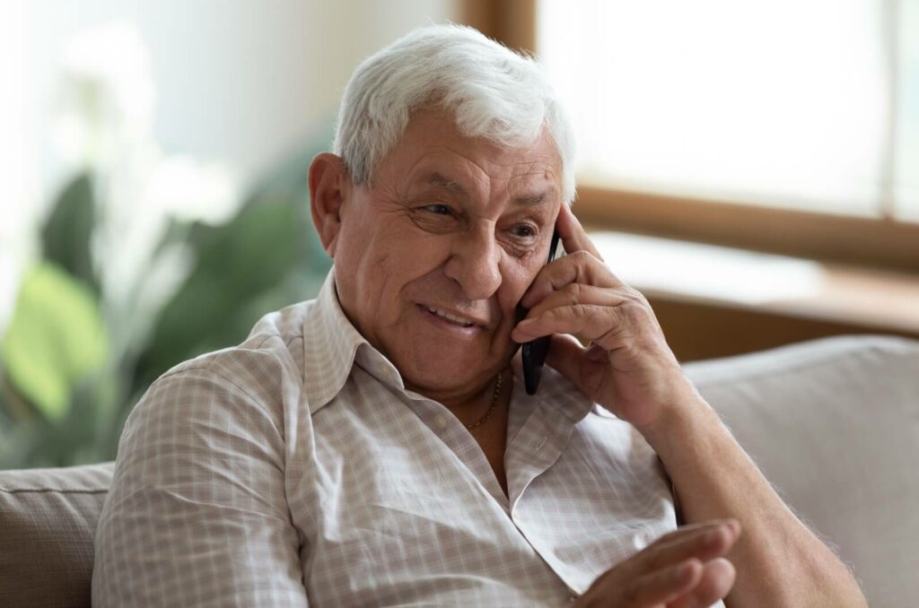 An older parent with dementia enjoying a phone conversation.