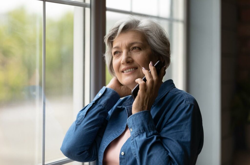 A parent with dementia smiling and talking on the phone.