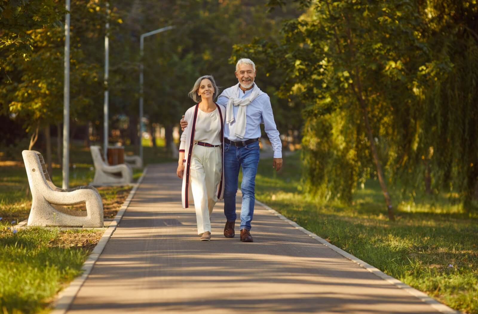 A happy older adult couple enjoy their daily walk together on a local walking trail.