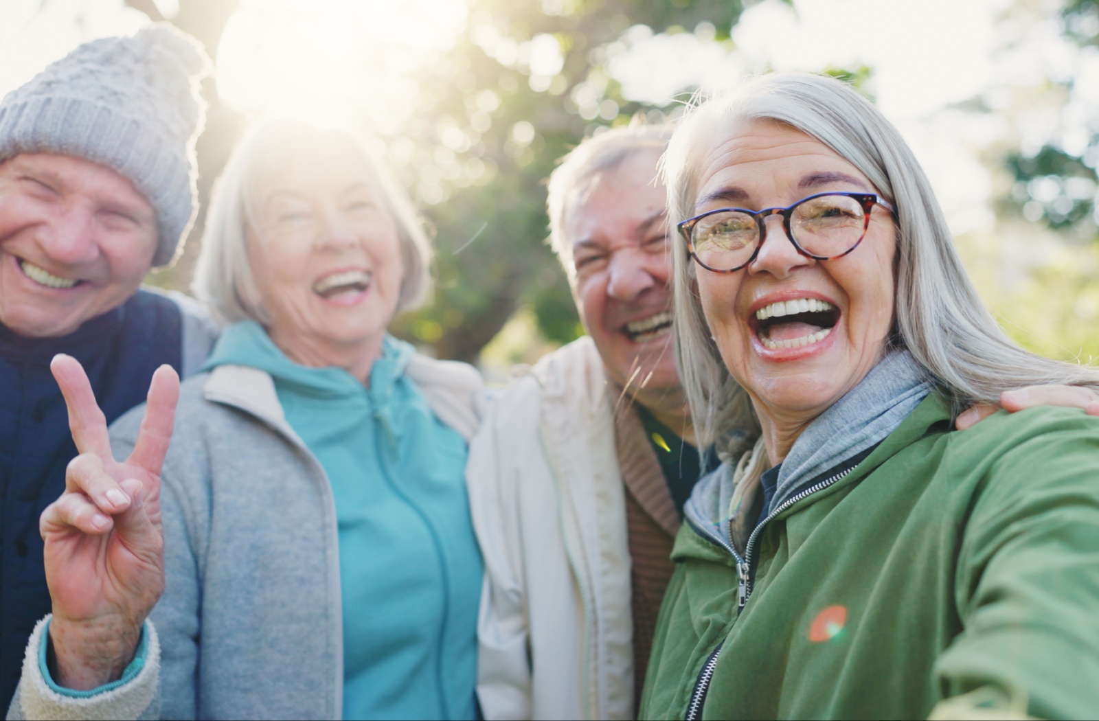 A group of happy older adults outside in the park and smiling for a picture.