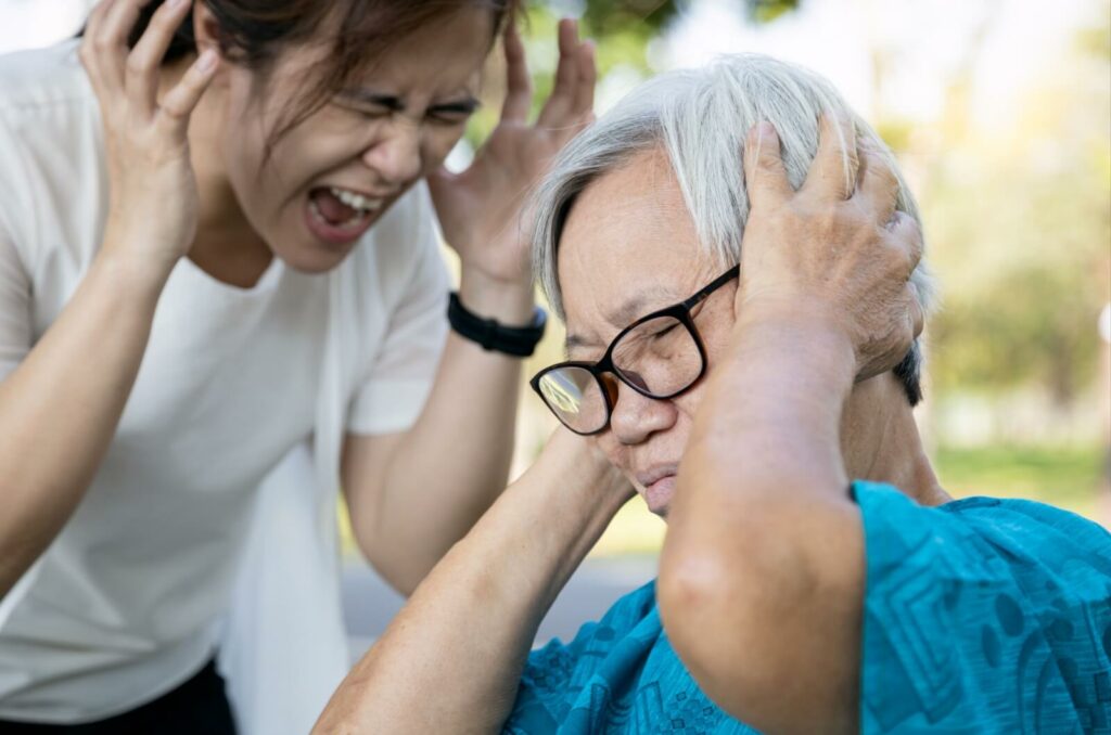 An adult daughter taking care of her mother, vents her frustrations, shouting and expressing the emotional strain of the caregiving responsibilities.