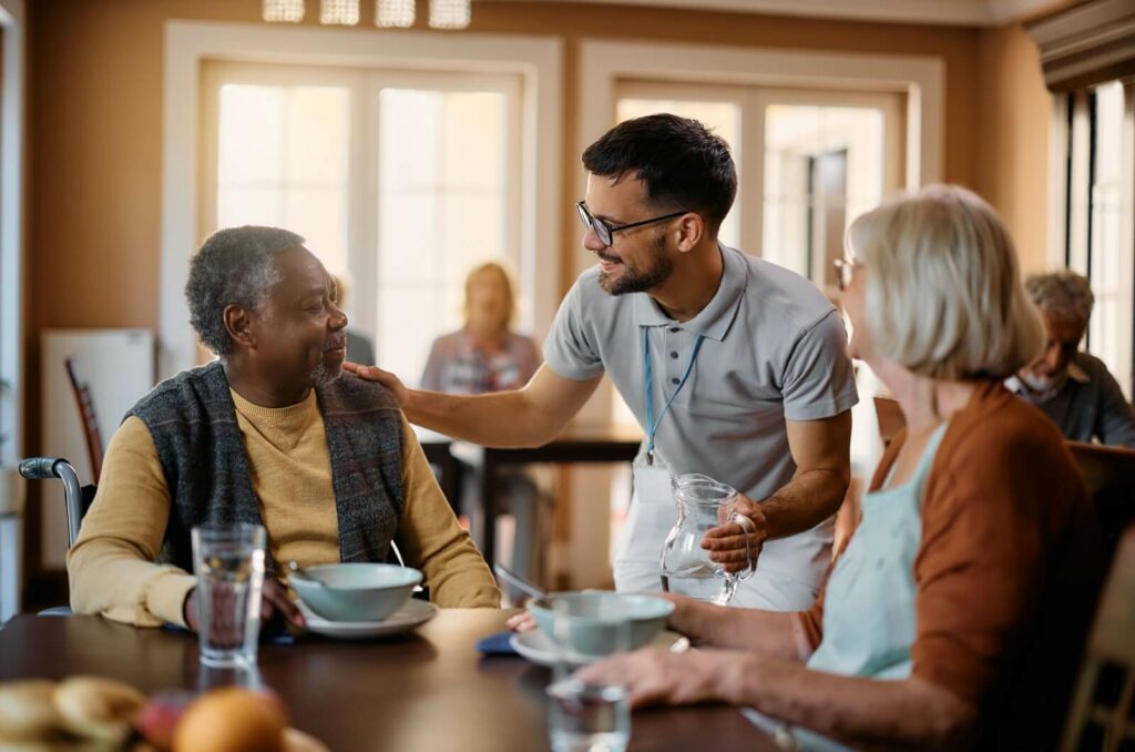 Professional caregiver checks in on 2 seniors during their mealtime.