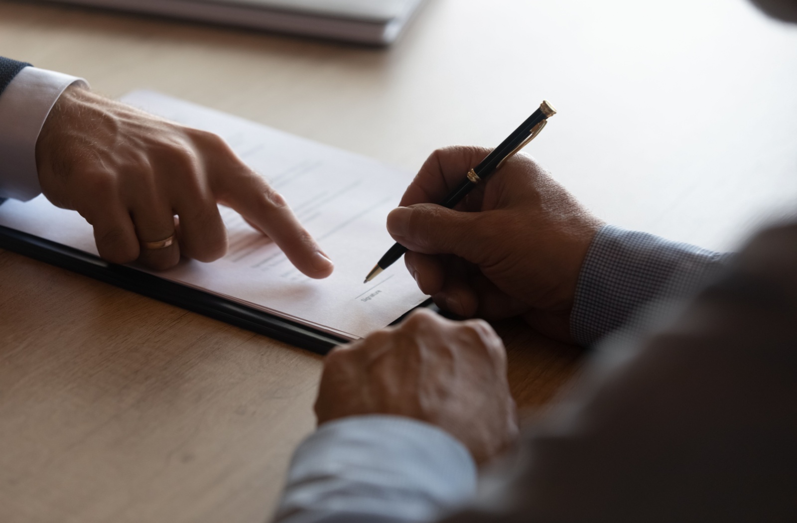 A close-up image of an adult child signing paperwork related to the tax deductions for their parent's memory care.